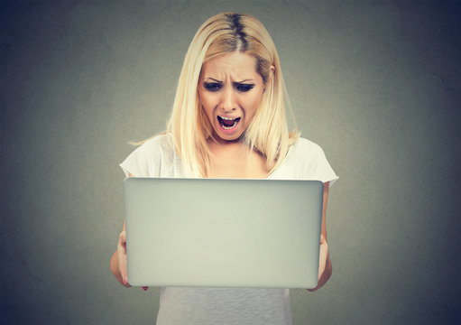 Shocked woman looking at laptop computer anxious with open mouth. Human emotion reaction 