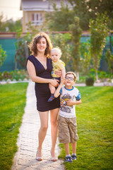 Fototapeta premium Young mother with two little sons in a park.