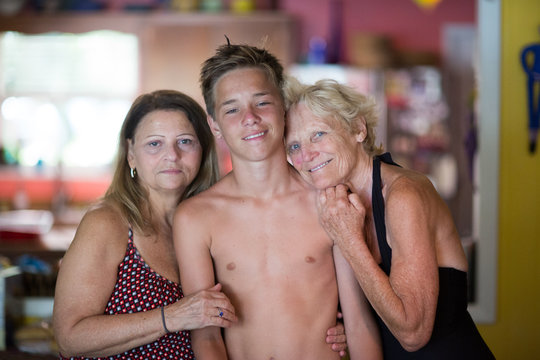 Family portrait, two senior women hugging teenage boy
