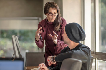 Businesswoman explaining to young male designer at home desk