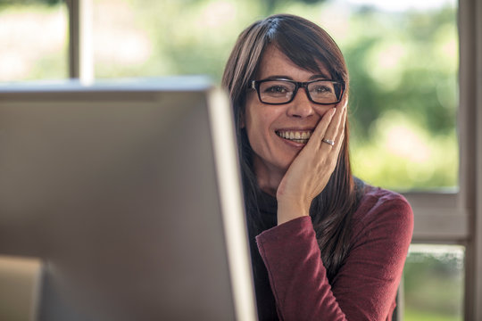 Happy businesswoman with hand on face at home desk