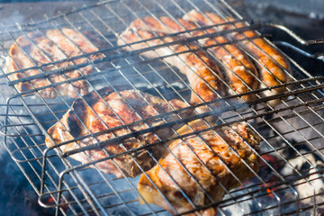 Meat and sausages are fried in a street grill, close-up