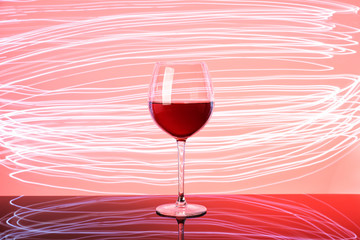 Glass of red wine on neon glow. Silhouette of glass on pink and claret background. 