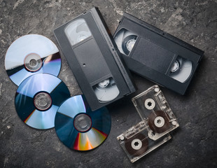 Entertainment and media technology from the 90s. CD's, audio cassettes, video cassettes on a black...