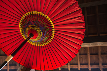 Traditional Japanese umbrella on a wooden house wall background.