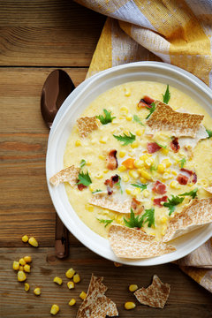 Corn chowder soup with bacon. Brown wooden background. Top view