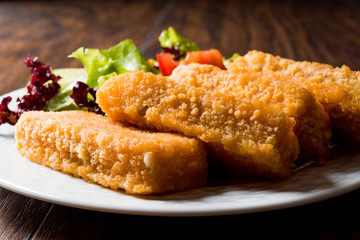 Fish Fingers with Salad on dark wooden surface.