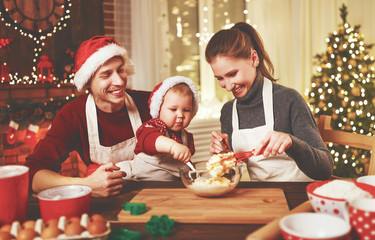 family mother father and baby bake christmas cookies.
