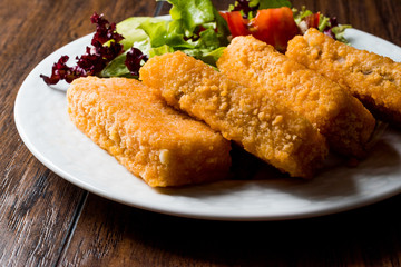 Fish Fingers with Salad on dark wooden surface.