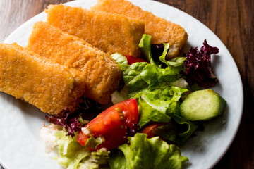 Fish Fingers with Salad on dark wooden surface.