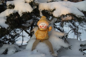 Happy and funny snowman on a branch of a Christmas tree in the snow