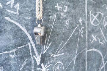 Fototapeta na wymiar whistle of a soccer coach / referee on black board with strategy drawing