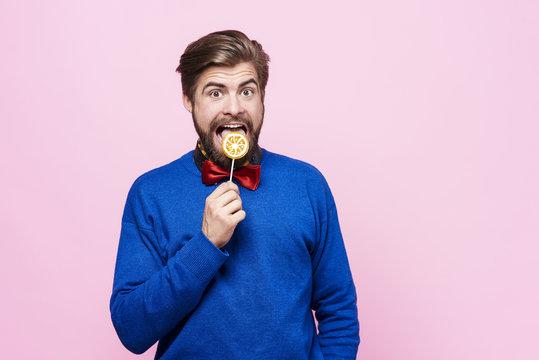 Man licking a lollipop at studio shot