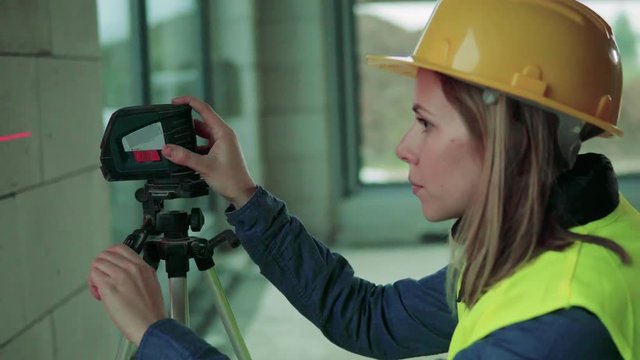 Young woman worker with laser on the building site.
