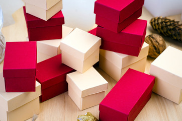 Stack of red and beige gift box and Christmas decoration on wooden background