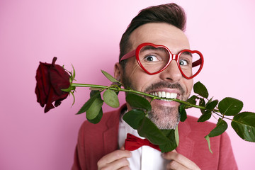 Man holding a rose in mouth .