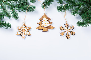 Christmas frame with the branches of the Christmas tree and wooden decorations on white background. Simple Christmas composition with free space