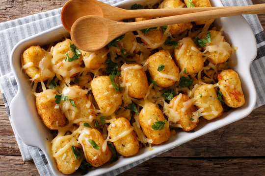 Casserole of Tater Tots with cheese and herbs close up in a baking dish. Horizontal top view