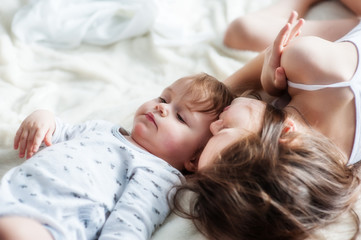 Two little girls lie on the bed together, head to head.