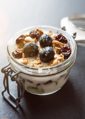 yoghurt with grapes, muesli crumble and cranberries in preserving jar