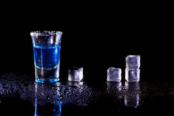 Whiskey in glass shots  with ice cubes on black background.
