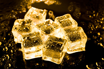 ice cubes and water drop on light golden background.