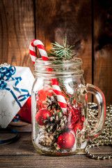 Christmas, New Year's concept. Mason Jar with Christmas decorations, fir cones, artificial snow, candy cane and fir branch. On a wooden table background. Copy space