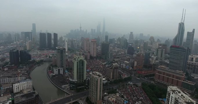 SHANGHAI, CHINA – JUNE 2016 : Aerial shot in central Shanghai on a misty day with skyscrapers, canal and Shanghai Tower in view