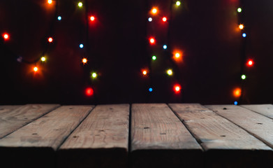 Christmas and New year background with blank dark wooden table on a background of bokeh lights.