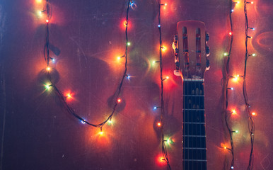 Old acoustic guitar with a garland on grunge background,