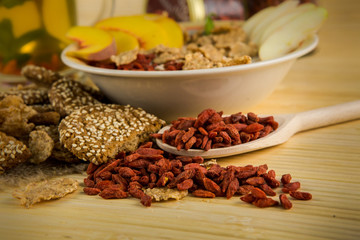 red goji berries in big wooden spoon near big bowl with porridge