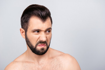 Obraz premium Close up portrait of emotional man with dislike emotion on his face, looking to the side, standing over grey background
