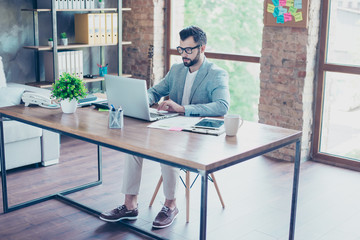 Young, clever, attractive, hardworking accountant sitting in workstation, concentrated on  work, using computer, looking at the screen