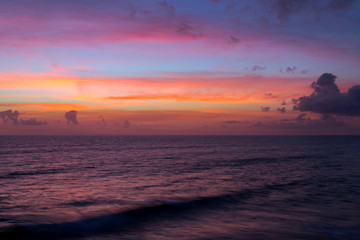 Dramatic pink sunset clouds over water sea. Seascape landscape at dusk