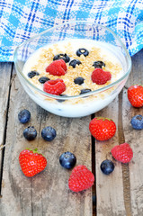 White yogurt in a bowl with oatmeal, blueberries, raspberries and strawberries