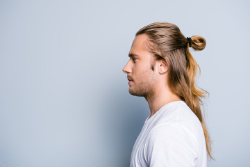 Close up side view photo of serious confident young guy, he has hair bun, isolated on grey background