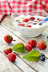White yogurt in a bowl with oatmeal, blueberries, raspberries and strawberries