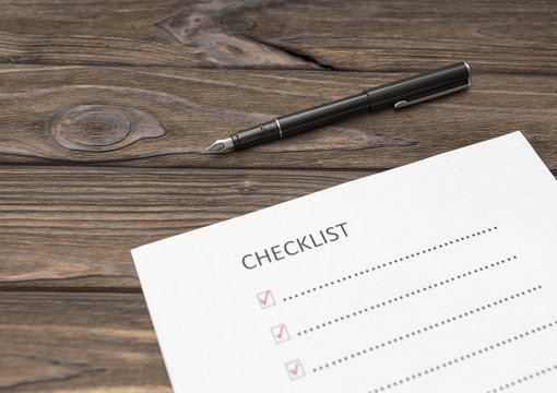 a checklist on a sheet of paper, a pen on a wooden table