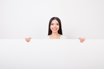 Copy space portrait of charming, attractive, cute girl hiding, standing behind empty white horizontal wall isolated over white background