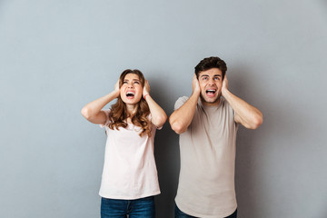 Portrait of an annoyed couple covering ears