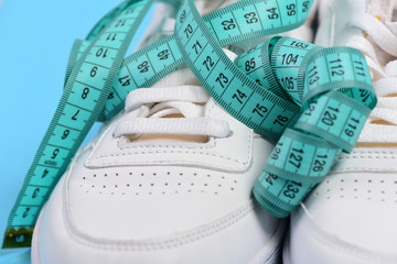 Sneakers with measuring tape on cyan background.