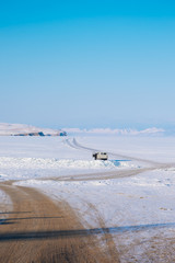 A long road to a frozen lake. The frozen lake Baikal in Russia during winter and car can run on the lake surface. The sky is clear and bright blue.