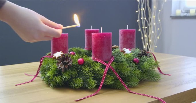 First Sunday of Advent - a young woman is lighting the first candle of the advent wreath - ProRes