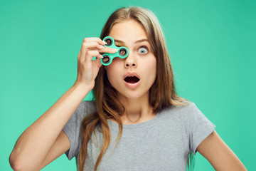 Beautiful young woman on a green background holds a spinner, toy, emotions, portrait