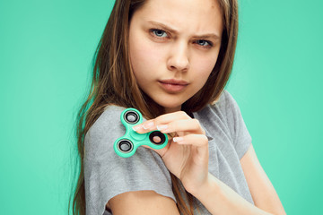 Beautiful young woman on a green background holds a spinnet spinner, toy