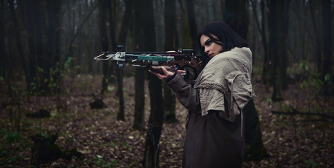 Girl with a crossbow in the forest. Autumn forest. - obrazy, fototapety, plakaty