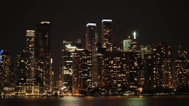 Night city - glowing skyscrapers are reflected in the water. View from the floating ferry. Toronto, Canada