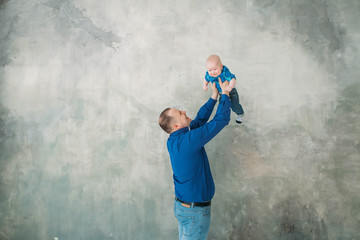 Obraz na płótnie Canvas Happy family portrait father and little son standing on gray background white floor room sunny day