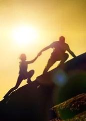  The joint work teamwork of two people man and girl travelers help each other on top of a mountain climbing team, a beautiful sunset landscape. The silhouettes on top of a mountain © gerasimov174
