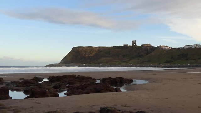 Low angle view of sandy beach of Scarborough in North Yorkshire, England at dusk and castle ruins on the cliff